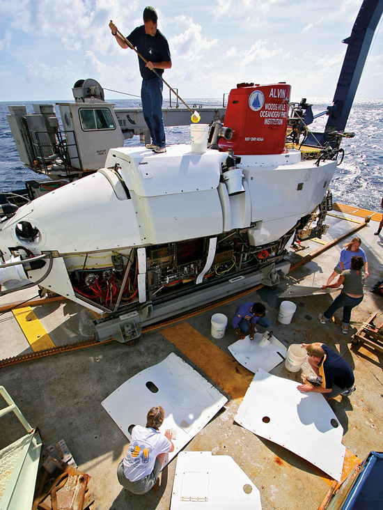 Working on the deck of the research vessel Atlantis, pilots and technicians from the Alvin Group scrub down the submersible between dives.