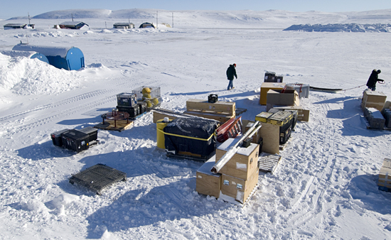 Arriving safely in Resolute, the many crates and bins of science gear are stacked up in the yard outside a research warehouse.