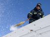Travis Goetzinger sweeps the frost off of the wings of the Twin Otter in preparation for takeoff.
