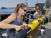 Summer Student Fellow Tess Brandon and Engineering Assistant Amy Kukulya working with a REMUS at the dock.