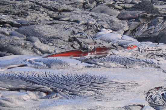 Fresh lava makes beautiful glowing landscapes. Here lava is emerging from beneath a solidified crust and pooling in nearby shallow depressions.