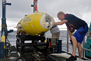 Fred Wendt  of IFM Geomar and WHOI research specialist Mark Dennett (partially hidden) inspect the  REMUS 6000 autonomous underwater vehicle owned by the WAITT Institute as it is positioned on the LARS (Launch and Recovery System) during the April 2011 search for Air France Flight 447.