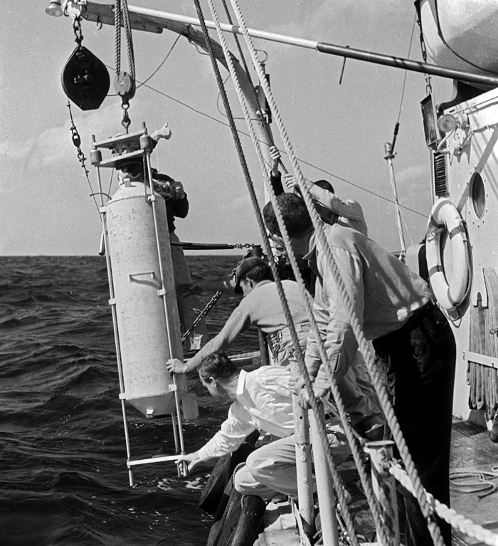 researchers on ship with person-sized sampling bottle