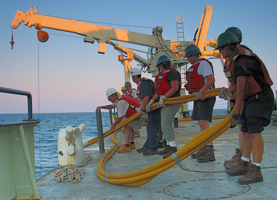Chief Scientist John Goff (blue t-shirt and jeans) and other science staff are deploying a Vibracorer off the R/V Knorr.
