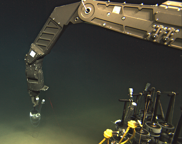 ROV Jason's manipulator arm inserts an injection pushcore into the seafloor near a DHAB