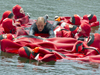 ten people in survival suits form a raft to support an unsuited person