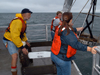 Hovey Clifford helps two summer student fellows deploy a grab sampler