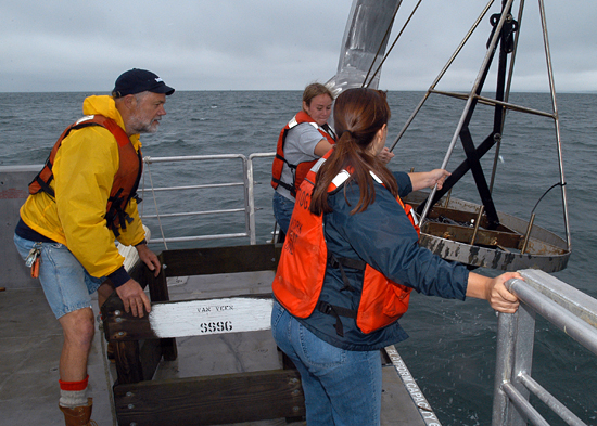 Hovey Clifford helps two summer student fellows deploy a grab sampler