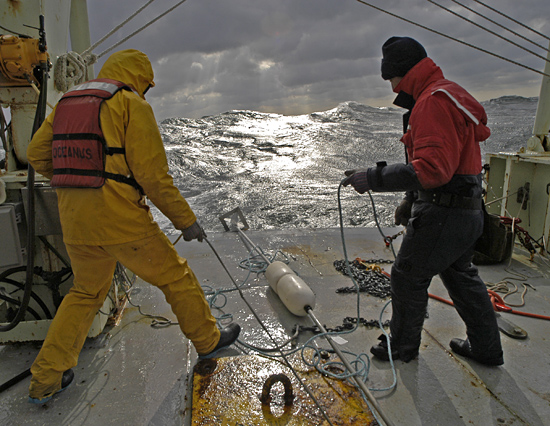 Veteran seagoing WHOI researchers Craig Marquette (left) and Will Ostrom deploy a mooring with tiny temperature probes from R/V Oceanus during a gale off Cape Hatteras
