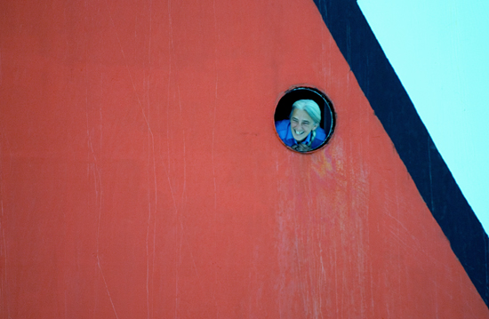 From onboard the Canadian icebreaker Louis St-Laurent, Steward Judith Joncas peers out from a porthole.