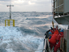 Researchers and crew members struggle to deploy a spar buoy in rough seas.