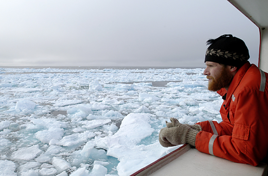 Jeremy Kaspar, a student at the University of Alaska, Fairbanks, keeps a watchful eye on the icy ocean from onboard USCG Healy.