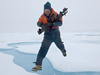 John Kemp leaping across ice gap carrying drill bits for ITP deployment.