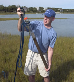 Assistant Scientist Jeff Donnelly holds a core of mud and sediment pulled up from a marsh.