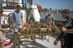 WHOI Assistant Scientist Peter Traykovski (left), Senior Research Assistant Jay Sisson, and a professional diver examine an instrument tripod covered with hydroids and mud after six months on the bottom of the Hudson River.