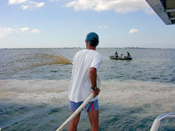 Scientist Mike Henry of the Mote Marine Laboratory sprays clay slurries into Florida’s Sarasota Bay while WHOI Postdoctoral Investigator Mario Sengco and colleagues in the other boat track the dispersal of the plume with water sampling devices.
