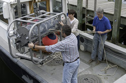 WHOI researchers Alexi Shalapyonok, Heidi Sosik, and Robert Olson (left to right) carefully load the FlowCytobot onto a WHOI research vessel for installation on the seafloor at the Martha’s Vineyard Coastal Observatory.