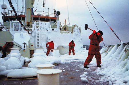 Captain A.D. Colburn, right, crew member Bill Dunn, and others wield their ice mallets on <em>Knorr's</em> foredeck during the Labrador Sea cruise.
