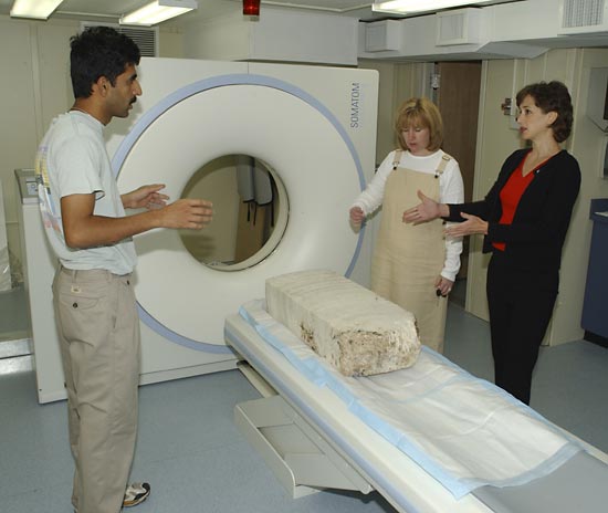 A large core section of coral, with an intricate internal canal structure that once housed coral polyps, is positioned on the scanner bed by scientists Anne Cohen and Hanumant Singh with Arruda.