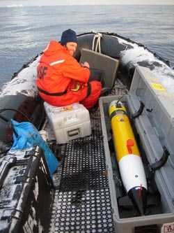 Greg Packard, in an inflatable boat, prepares to launch a REMUS (Remote Environmental Monitoring UnitS), to measure ocean bottom depths in a pre-determined area and pattern around Palmer Station, part of a 5-week survey resulting in a new chart of the area. (Photo by Keith von der Heydt, WHOI)