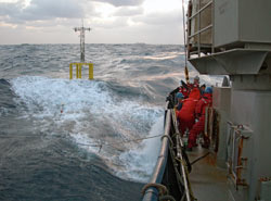 Researchers and crew members struggle to deploy a spar buoy in rough seas