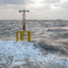 Researchers and crew members struggle to deploy a spar buoy in rough seas