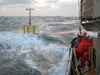Researchers and crew members struggle to deploy a spar buoy in rough seas