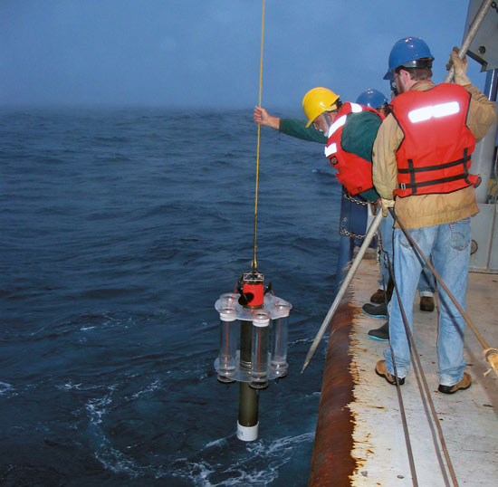 WHOI biogeochemist Ken Buesseler (blue hat) and engineer Jim Valdes (yellow hat) deploy a Neutrally Buoyant Sediment Trap for a three-day mission in the depths of the North Pacific Ocean in 2005. The instrument collects ?marine snow.?