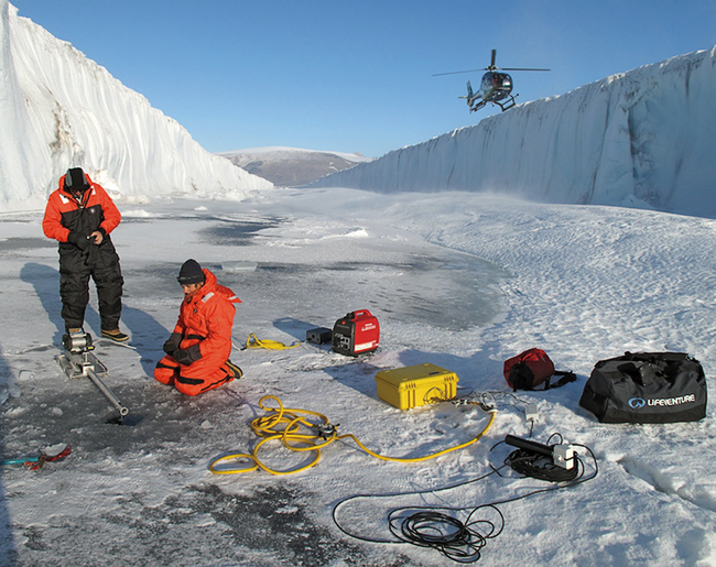 Fiamma Straneo (kneeling) and colleagues to drill through it to sample water within the fjord below.