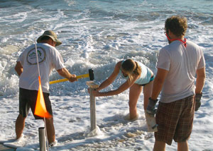 Worker hammers core tube into beach