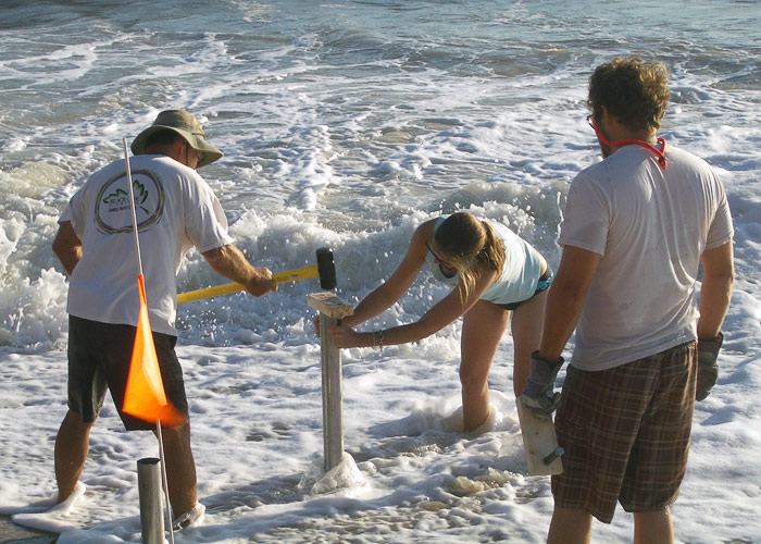 Worker hammers core tube into beach
