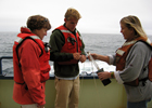 Amy, graduate student Dave Sutherland, and unidentifiied crew member collect a water sample