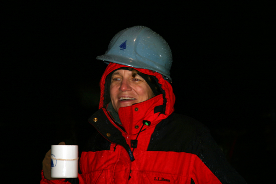 On the rainy deck of the <em>Knorr</em>, Amy Bower, drinking hot chocolate to keep warm, watches,  as the mooring slowly unspools.