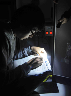 By flashlight on the upper deck, Hiroomi Miyamoto from Tokyo University pours through the Japanese version of the aerosol sampler operating instructions to determine why a sampler on board would not start.