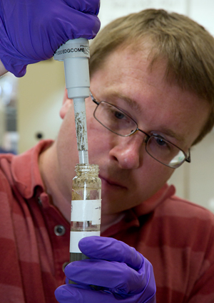 research associate Dave Beaudoin uses a pipet to collect microbes from a test tube