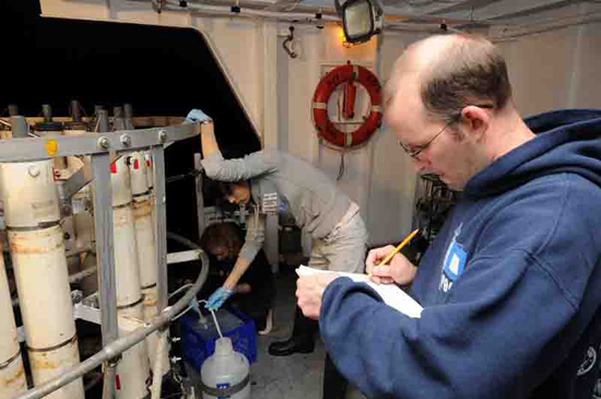 With all the samples being gathered with different handling requirements, every rosette requires a bottle cop to ensure that the correct amounts are put in the correct containers. Here, Steve Jayne acts as bottle cop while Kamila Stastna (left) and Sachiko Yoshida tap the correct bottles from different depths.