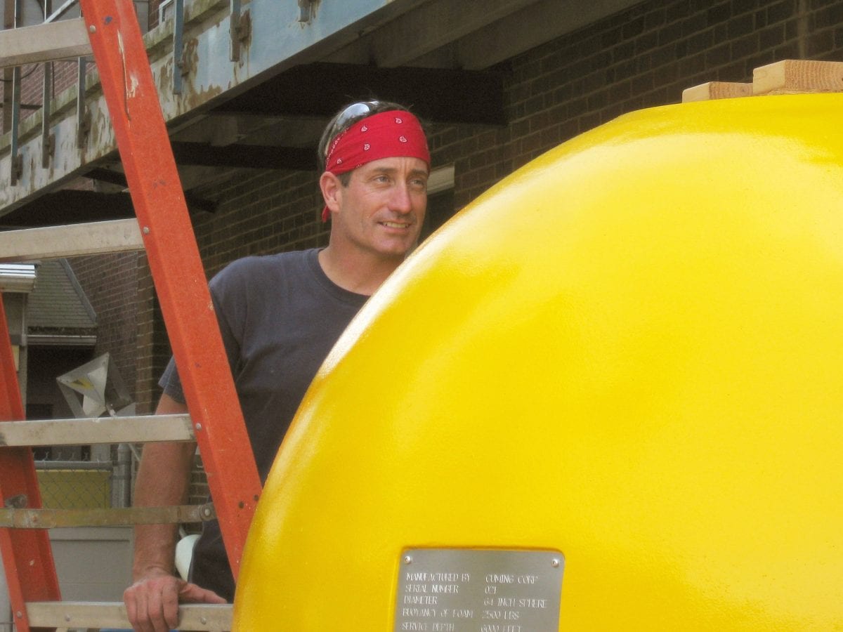Joe Fellows prepares a syntactic sphere outside the Mooring Lab