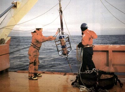 Two ADCPs are often lowered together, one facing the surface and the other facing the bottom, to double the length of the current profile. The metal cage around the ADCPs that Senior Engineering Assistant Scott Worrilow of the Woods Hole Oceanographic Institution is helping overboard holds the instruments in place and protects them from accidental bangs against the ship's hull. (Claudia Cenedese)