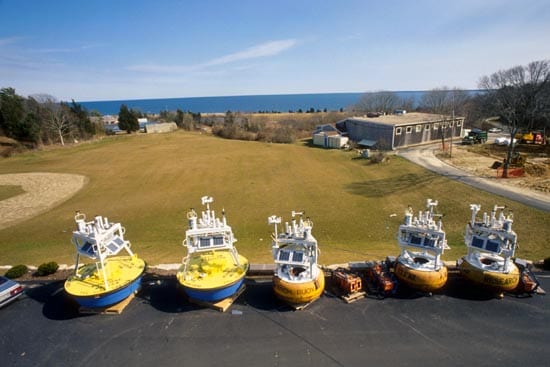 Two early 1990s buoy designs during instrument burn-in at the WHOI lab. Toroid, or donut-shaped, buoys (right) were replaced by larger aluminum discus buoys (left).By 1995, solar panels were no longer in use. Augmenting battery power with solar energy seemed like a promising idea, but protecting the sensitive panels against waves and salt proved difficult. Instead, engineers reduced the system's power requirement by more than 90%. (photo courtesy Robert Weller, WHOI)