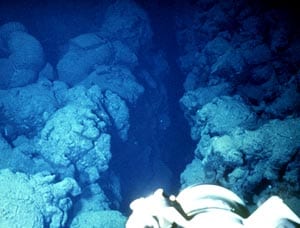 Submarine pillow flows along an eruptive fissure near the crest of the East Pacific Rise at 2600 meters depth. Scale across photo is about 4 meters. Camera across the foreground is one of Alvin’s video cameras.