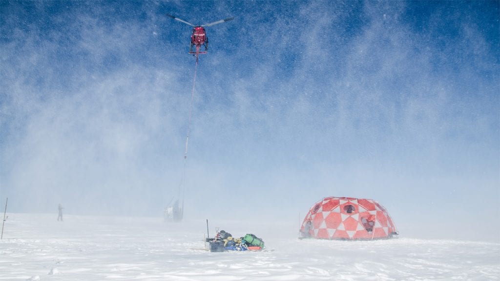 A helicopter takes off with a sling-load of freshly-drilled ice cores taken from the 2000-meter-high summit of an ice cap in west Greenland.