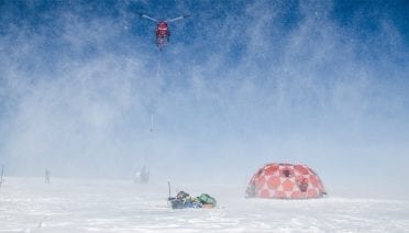 A helicopter takes off with a sling-load of freshly-drilled ice cores taken from the 2000-meter-high summit of an ice cap in west Greenland.