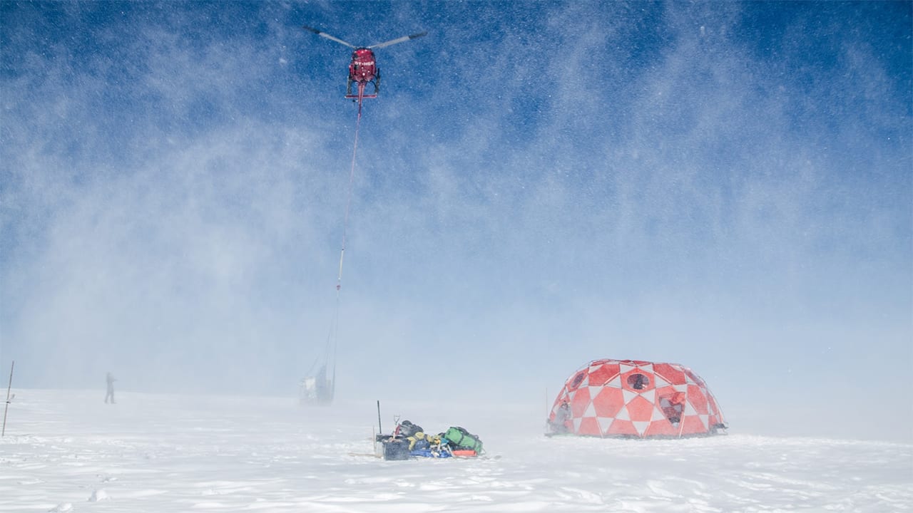A helicopter takes off with a sling-load of freshly-drilled ice cores taken from the 2000-meter-high summit of an ice cap in west Greenland.