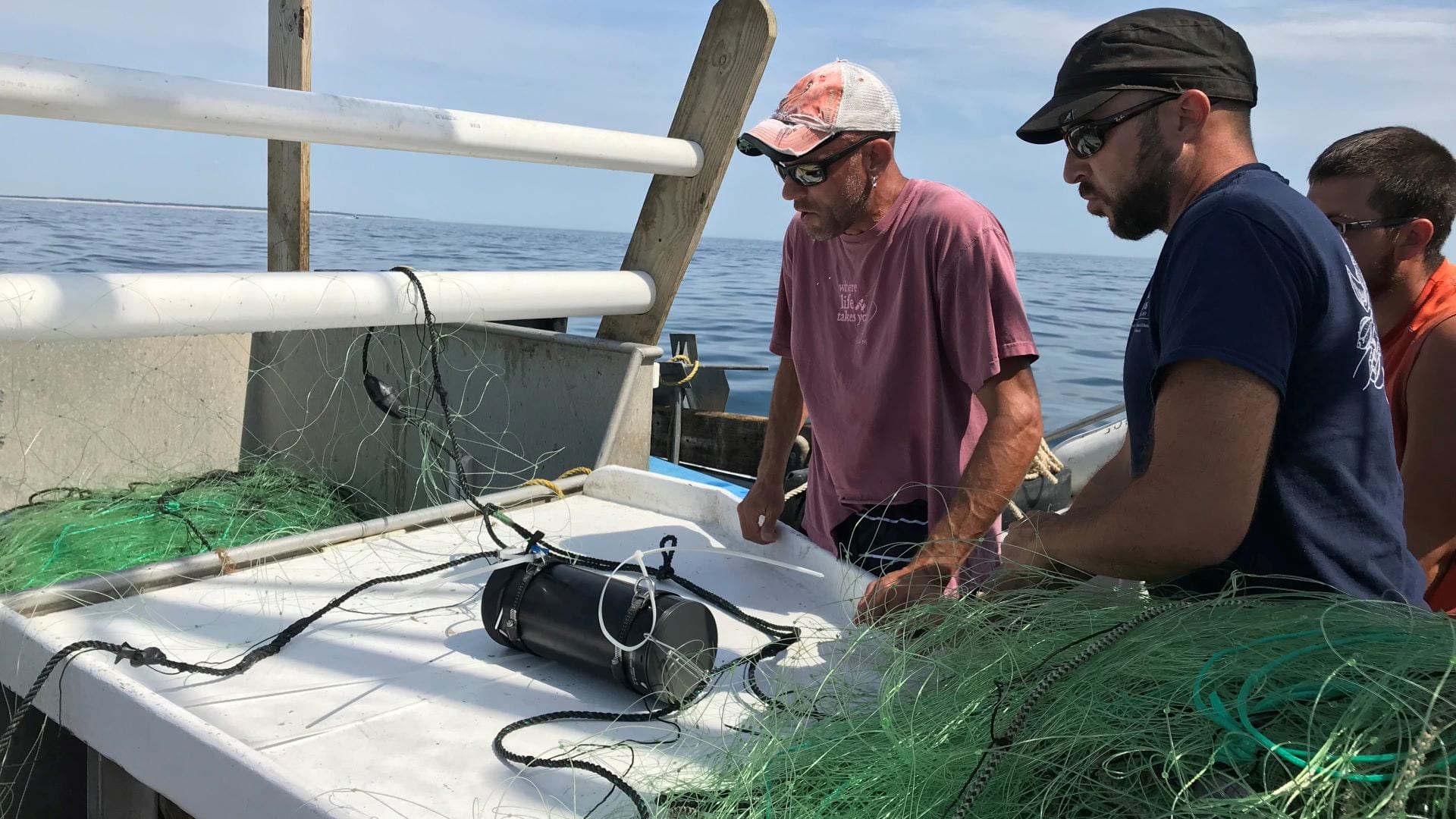 Commercial fisherman Doug Feeney (left) and scientist Owen Nichols from CCS mount one of five underwater cameras on the headrope of a gillnet