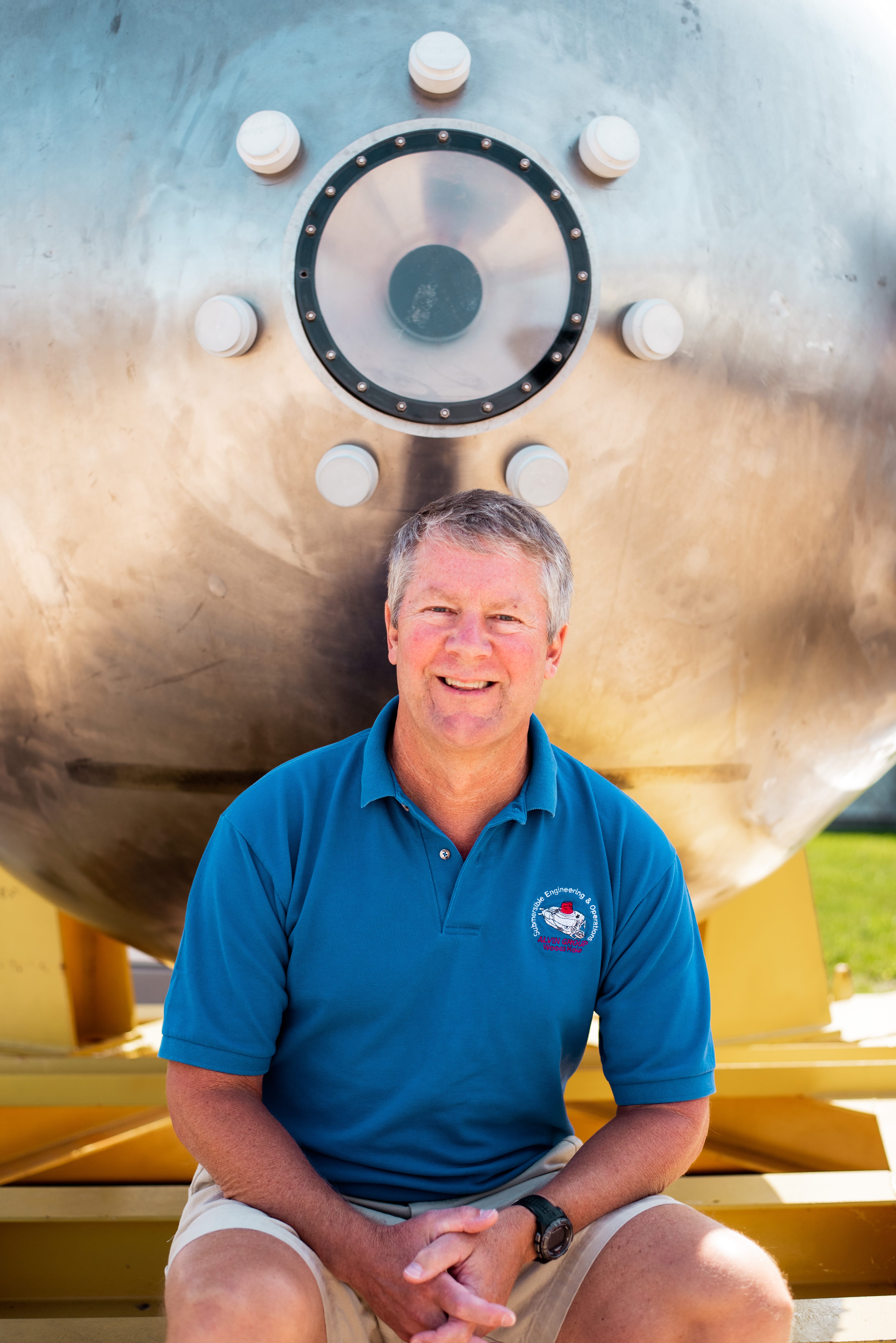 Rick Chandler sits beside 
the now-retired personnel sphere that once sat at the heart of <em>Alvin</em>'s frame. (Photo by Daniel Hentz, Woods Hole Oceanographic Institution)