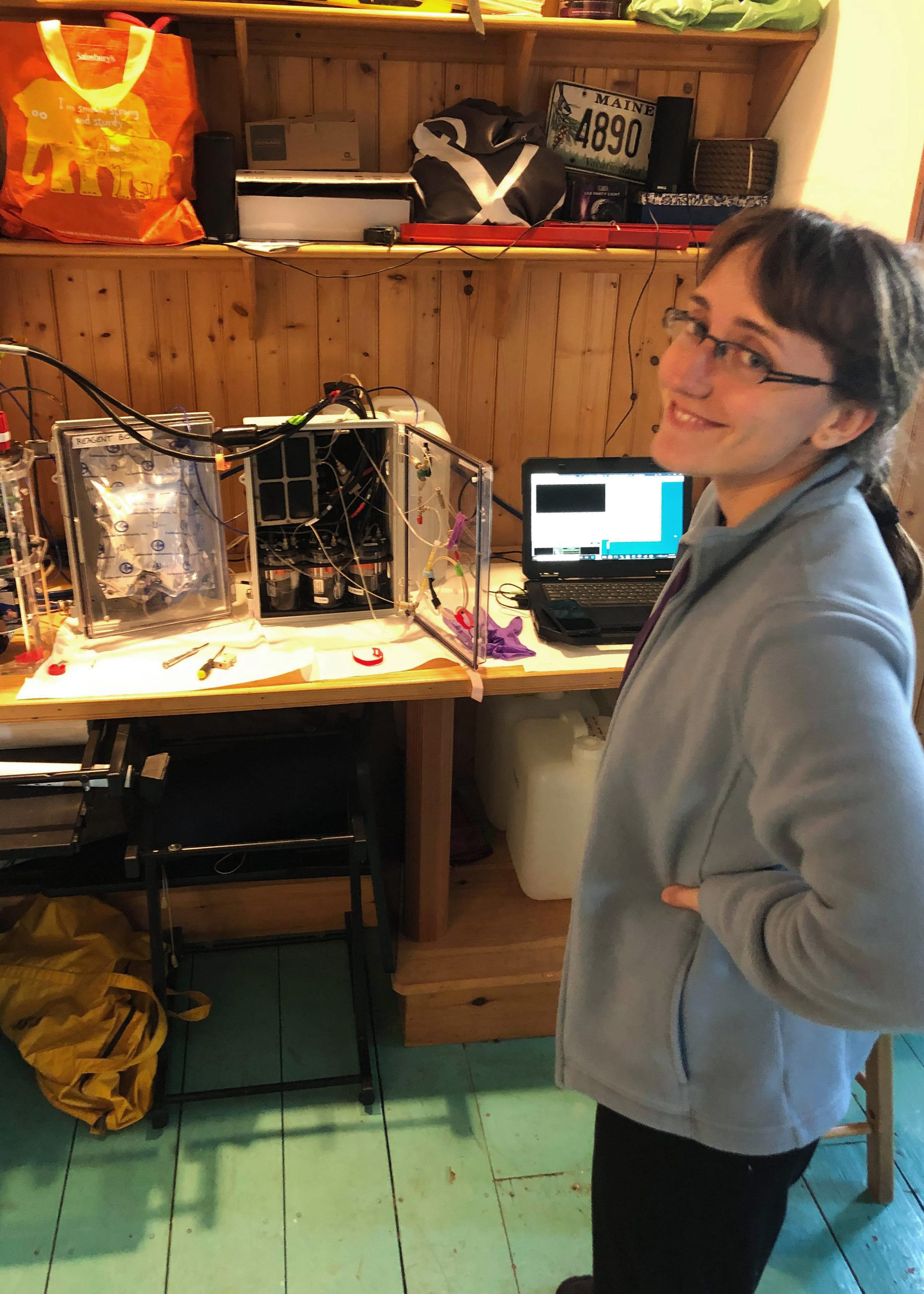 Mallory Ringham poses next to a disassembled CHANOS II, staged in her ersatz basement lab at her home in New York following stay-at-home orders. (Photo by Julia Middleton, © Woods Hole Oceanographic Institution)