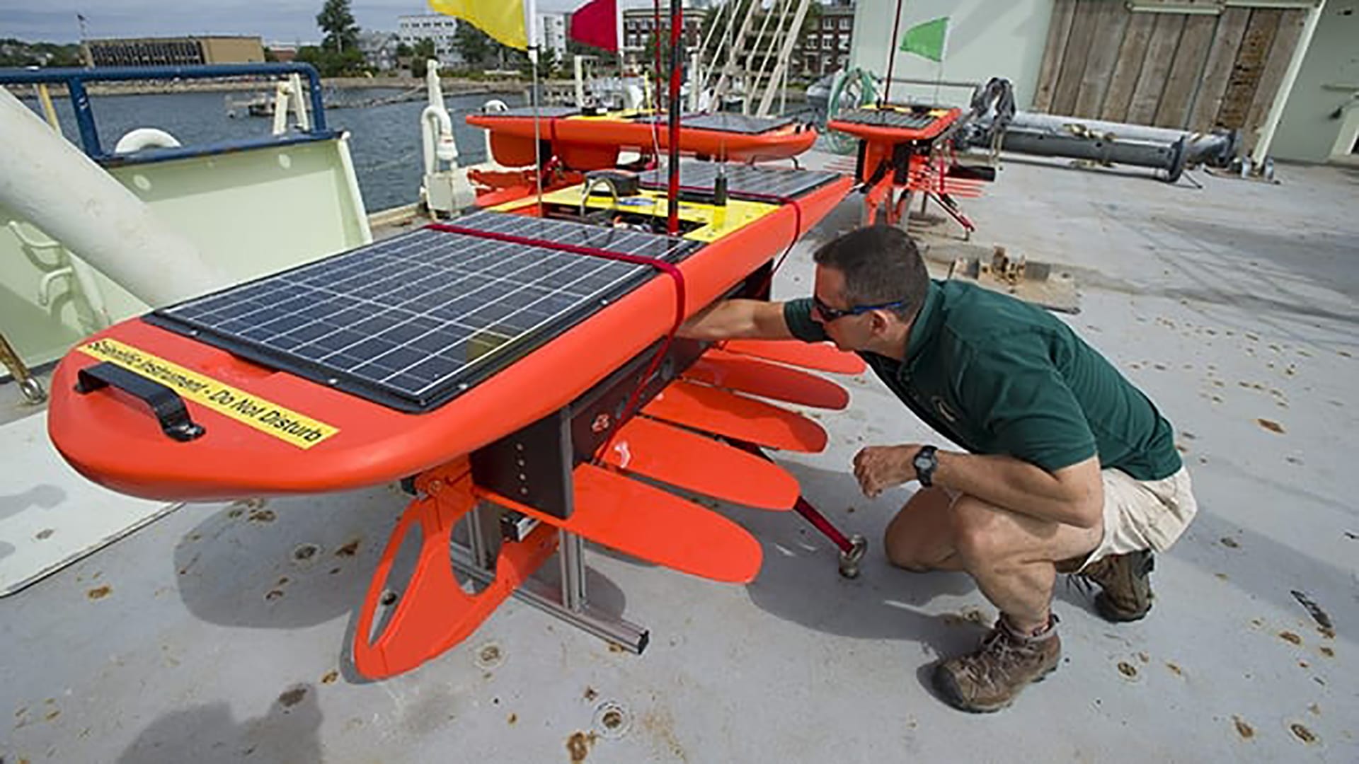 Former WHOI physical oceanographer Dave Fratantoni inspects a Wave Glider on the deck of R/V Knorr in 2012. The Wave Glider uses wave motion to propel itself through the ocean and solar-charged batteries to power its data collection sensors. (Tom Kleindinst, Woods Hole Oceanographic Institution)