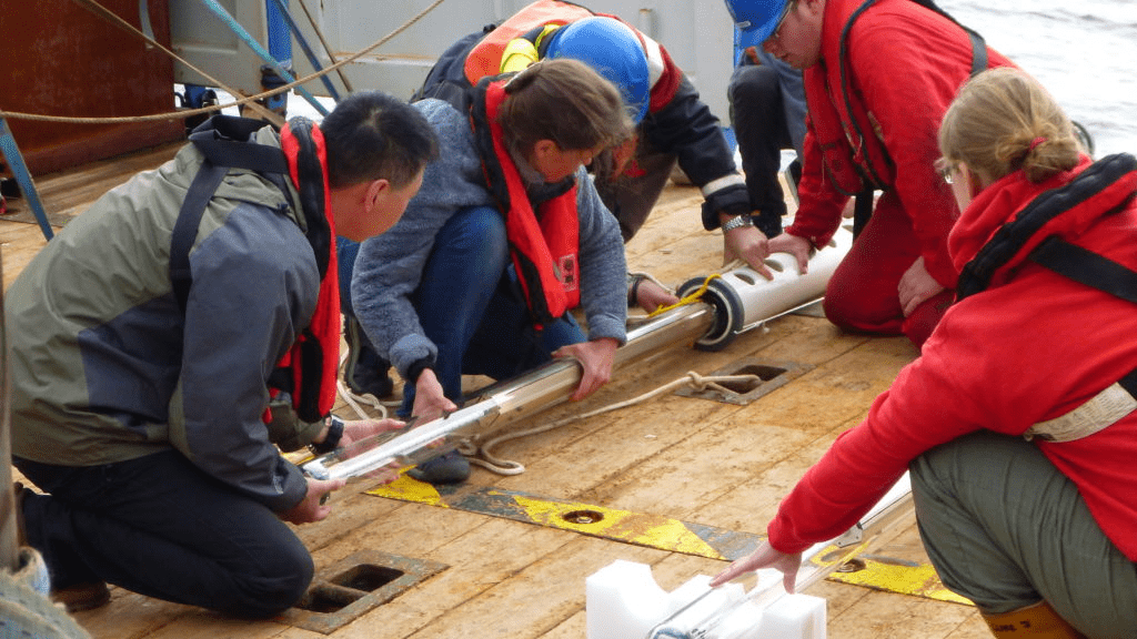 Science and ship's crew on deck preparing a subsurface float for deployment at sea.