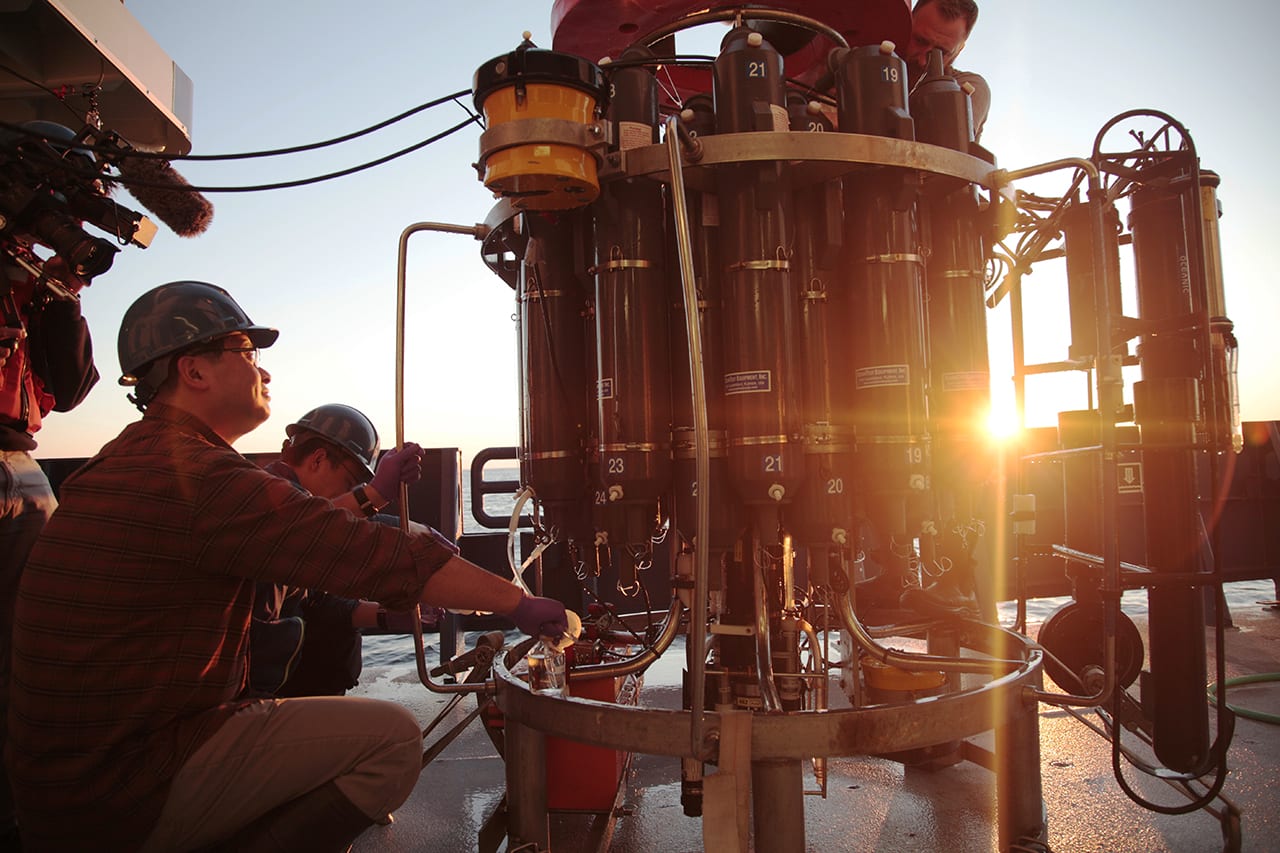 WHOI marine chemist Aleck Wang recovers samples from a CTD during a 2016 research cruise aboard the R/V <em>Neil Armstrong</em>, deployed along the New England Continental Shelf in the vicinity of the Ocean Observatories Initiative Pioneer Array. (Photo by Elise Hugus, UnderCurrent Productions)