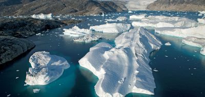 A large iceberg has broken away from the Helheim Glacier and floats among slabs of pack ice in Sermilik Fjord along the southeastern coast of Greenland. The glacier, about 3 miles wide at its mouth, has been shrinking rapidly in recent years. WHOI researchers are investigating whether changes in the fjords are contributing to the loss of ice. (Photo by Nick Cobbing © Greenpeace International)